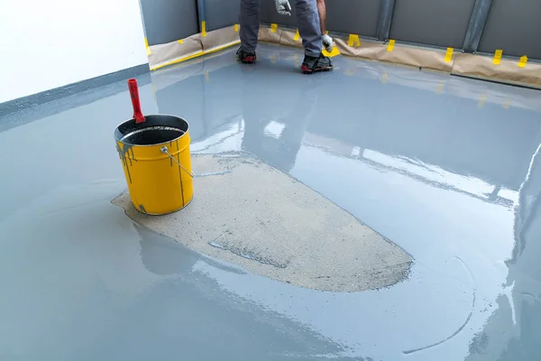 Construction worker renovates balcony floor and spreads watertig — Stock Photo, Image