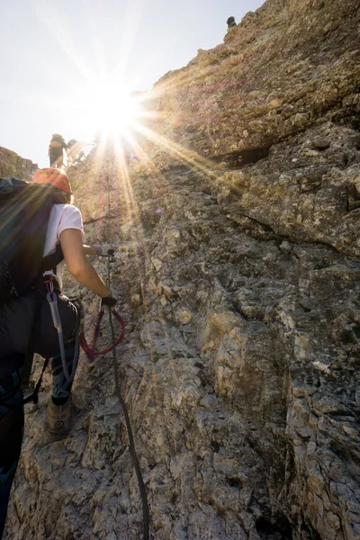 mountain climbers on a steep vertical climb in the Dolomites wit