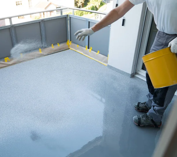 Construction worker renovates balcony floor and spreads chip flo — Stock Photo, Image