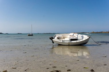 boats stranded in shallow water and sand on a deserted beach at  clipart
