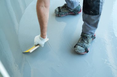 inşaat işçisi balkon zemini yeniler ve watertig yayılır