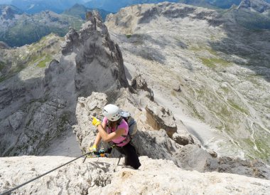 attractive brunette female climber on a steep and exposed Via Fe clipart