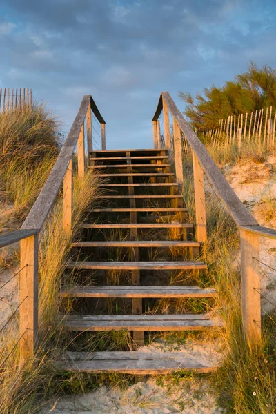 Escadas de madeira que conduzem sobre dunas de areia à praia na sagacidade do por do sol — Fotografia de Stock