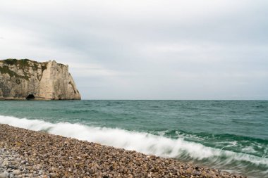 dalgalar t pürüzlü kayalıklar ile bir kaya ve çakıl plaj üzerine çökmesine