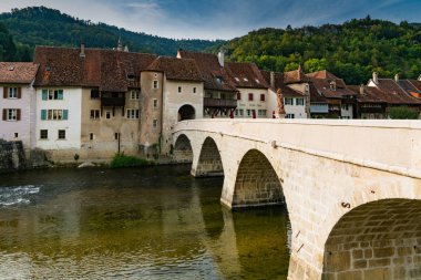 old stone bridge over a river leads to a picturesque historic Eu