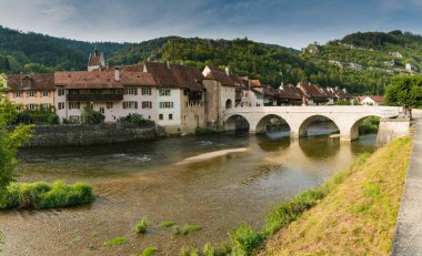 Doubs Nehri üzerindeki tarihi ve resimli İsviçre köyü Saint-Ursanne 'ın panoraması