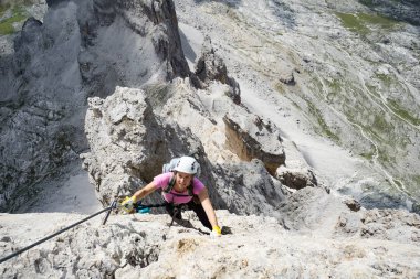 Çekici esmer kadın tırmanışçı dik bir yolda ve İtalyan Dolomitleri 'ndeki Via Ferrata' da açıkta.