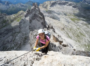 Çekici esmer kadın tırmanıcı dik bir yolda ve Via Ferrata 'da açıkta.