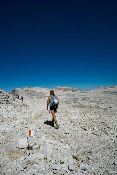 female mountain climber hikes across a wild rock desert high in the Dolomites of Italy