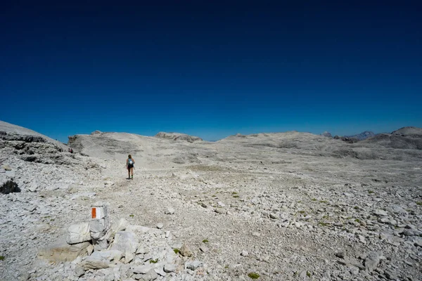 female mountain climber hikes across a wild rock desert high in the Dolomites after a hard climb