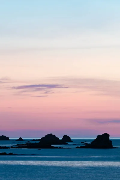 Zonsondergang aan het strand met een rustige oceaan en rotsen en riffen onder — Stockfoto