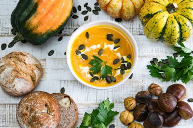 Kestane kabağı çerçeveli beyaz bir kasede organik balkabağı çorbası