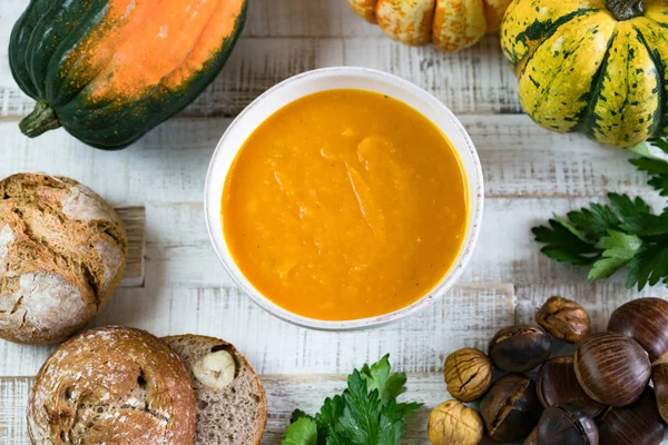 Kestane kabağı çerçeveli beyaz bir kasede organik balkabağı çorbası