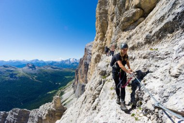 several mountain climbers on an exposed Via Ferrata in the Dolomites clipart