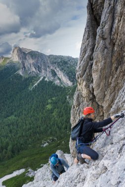 Yirmili yaşlardaki erkek ve kadın tatillerinde eğlenmek için dik bir Via Ferrata 'ya tırmanırlar.
