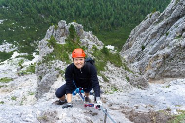 Alta Badia Dolomitleri 'nde, yirmili yaşlarında dik bir Via Ferrata' ya tırmanan bir kadın.