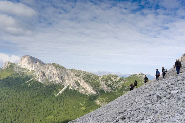 panorama view of a group of mountain climbers hiking up a mountain side to a hard climbing route