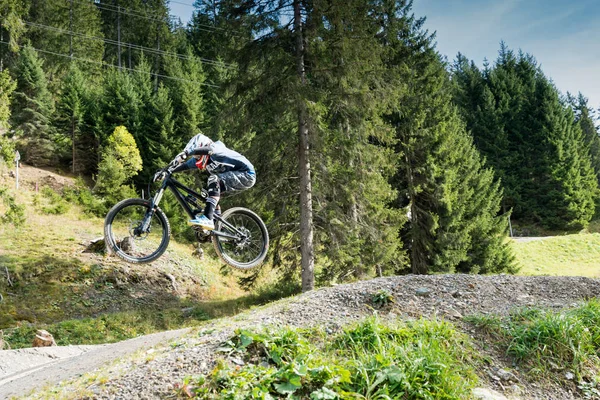 Ciclista de montaña cuesta abajo saltando alto y montando duro en Lenzerheide — Foto de Stock