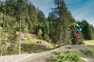 Yokuş aşağı dağ bisikletçisi yüksekten atlıyor ve İsviçre Alplerinde Lenzerheide 'de çok hızlı gidiyor.