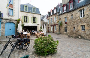 İnsanlar ön planda bisikletler olan huzurlu bir Fransız kafesinde yiyip içiyorlar.