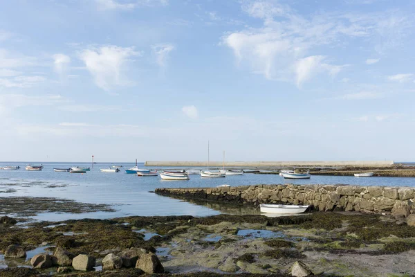 Many small boats anchored on a rocky coast in a small harbor at — ストック写真