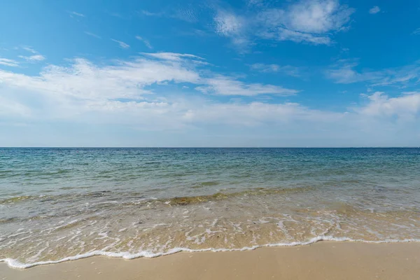 gentle waves on an empty sandy beach with a calm ocean