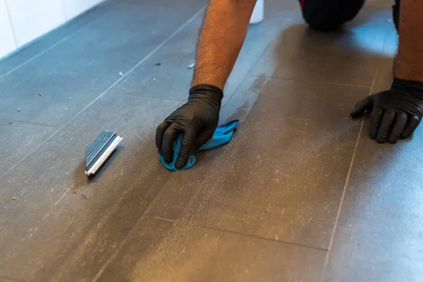プロの掃除機は 灰色のタイル張りのバスルームの床にブラシブレードと泡石鹸でグラウトを掃除します — ストック写真