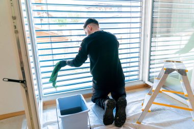 Profesyonel bir temizlikçinin yakın çekimi, yeşil bir mikro fiber bezi olan bir apartmanın penceresini kör eder.