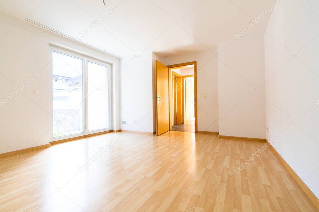 A low angle vertical view of new wooden parquet flooring in a bright light and white apartment room