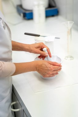 A close up view of a pharmacist in the laboratory mixing a medical ointment in a bowl clipart