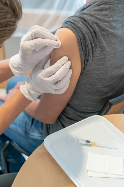 予防接種後の女性患者の腕を消毒する女性医師の垂直ビュー — ストック写真