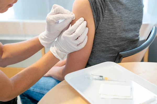 予防接種後の女性患者の腕を消毒する女性医師の水平的見解 — ストック写真