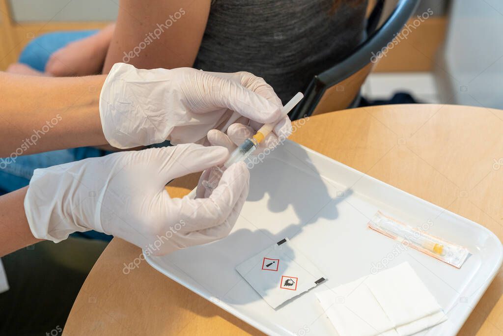 A female doctor preparing a one-way needle and syringe for a vaccination with a female patient