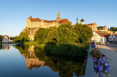 Sigmaringen, BW / Almanya - 12 Temmuz 2020: Tuna Nehri 'ndeki yansımalarla gün batımında Hohenzollern Şatosu Sigmaringen manzarası
