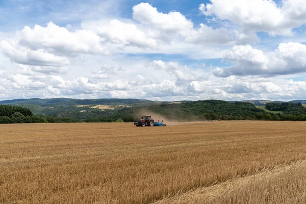 Een Rode Trekker Trekt Een Blauwe Veld Cultivator Een Geoogst — Stockfoto