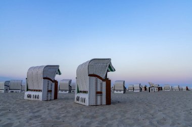 Sellin, M-V / Almanya - 15 Ağustos 2020: kumsalda beyaz plaj sepetleriyle güzel bir gün batımı ve plaj akşamı