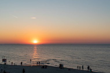 Polonya 'da Baltık Denizi' nde gün batımının keyfini çıkaran birçok insanın silueti.