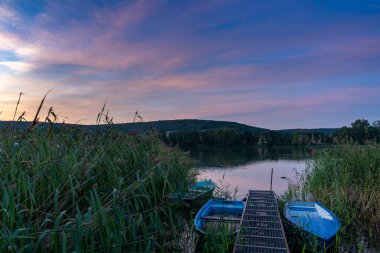 Göl manzarası üzerinde renkli bir günbatımı ön planda küçük kayıklar