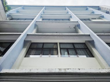 Solucan bakışı çok katlı bir binanın ön cephesinde tekrarlanan pencere ve beton balkon desenleri geometrik bir tasarım yaratıyor.