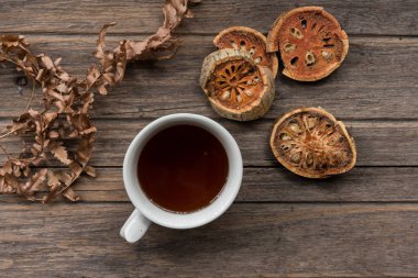 Kuru bael meyve ile ahşap arka plan üzerinde kurutulmuş bael suyu Fincan . ot suyu. En iyi görünüm konsepti.