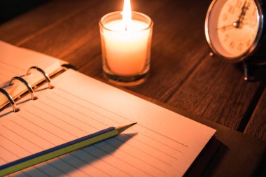 Günlük masada parlak alev ile yanan mum yanında kalem le açık / Anılar yaşam veya roman yazma kavramı / Bir kalem seçim odak.