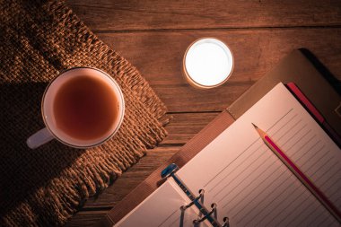 Günlük masada parlak alev ile yanan mum yanında kalem ve sıcak içecek ile açık / Anılar yaşam veya roman yazma kavramı / Bir kalem için Top view fotoğraf seçimi odak.