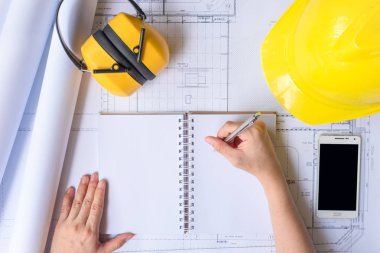 Mühendis kişi sarı kask ile tasarım konsepti oluşturmak için çalışıyor. Kopyalama alanı ile yukarıdan üstten görünüm.