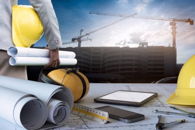 İnşaat mühendisi masası., bina inşaatına karşı plan ve güvenlik ekipmanları ile çalışma.