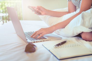 Kadınlar akıllı telefonları tutarken yatak odasındaki kablosuz bağlantıyı kullanıyorlar. Teknolojiyi her yerde modern cihazlar için kullanıyorlar.