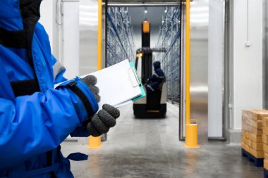 Dondurucu odada veya depoda malları kontrol etme panosu olan işçinin eli