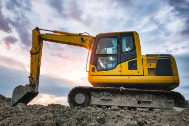 Gün batımı gökyüzü bulutları üzerinde şantiyeayakta Ekskavatör makinesi