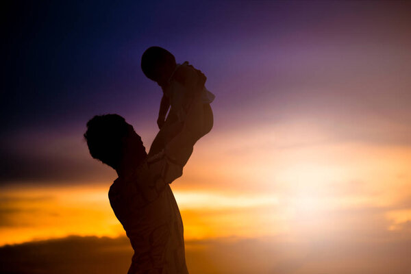 Father holds his child with love. silhouette on the sunset time