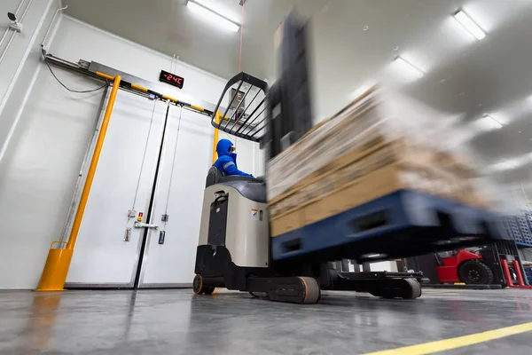 Worker Stand-on stacker truck used to lift and move the ready meals goods stock in cold room or freezer room.