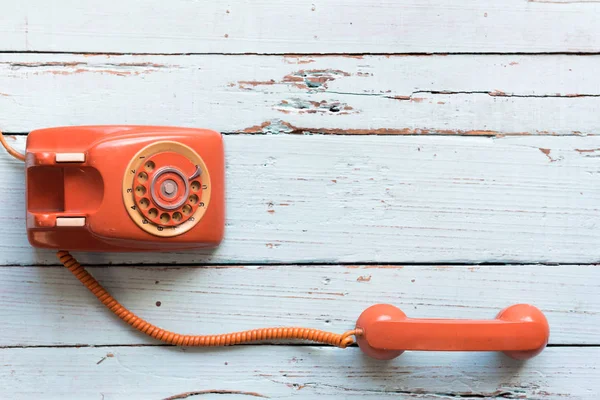 Retro orange-red telephone on the old wooden table with copy space for text or your subject in the past.